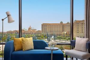リヤドにあるThe St. Regis Riyadhの大きな窓付きの客室で、青いソファが備わります。