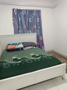 Schlafzimmer mit einem Bett mit einer grünen und weißen Bettdecke in der Unterkunft Homestay Danau Ria @ Gamuda Gardens in Pengkalan Kundang