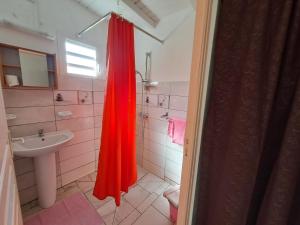 baño con cortina de ducha roja y lavamanos en O 4 épices gites, en Capesterre-Belle-Eau