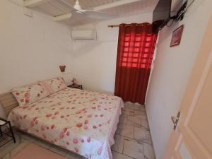 - une chambre avec un lit et un rideau rouge dans l'établissement O 4 épices gites, à Capesterre-Belle-Eau