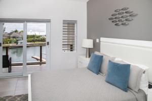 a white bedroom with a bed with blue pillows at 246D South Finger in Jolly Harbour