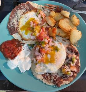 a blue plate of breakfast food with eggs and potatoes at Airport Inn Roatan in Coxen Hole