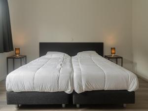 een groot bed met witte lakens en 2 nachtkastjes bij Nice holiday home in Simonshaven with garden in Simonshaven
