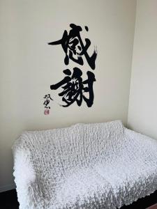 sypialnia z łóżkiem z chińskim napisem na ścianie w obiekcie GUEST House彩 w Osace