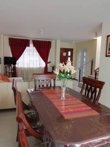 a dining room table with a vase of flowers on it at Casa, Hospedaje Turístico. in Otavalo