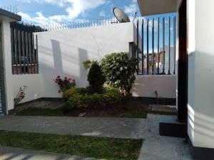 una cerca blanca con un arbusto al lado de un edificio en Casa, Hospedaje Turístico., en Otavalo