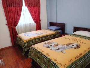 Dos camas en una habitación con dos perros. en Casa, Hospedaje Turístico., en Otavalo