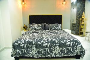 a bed with a black and white comforter and pillows at Chic Noir 1 Bedroom Apartment Gulberg in Lahore