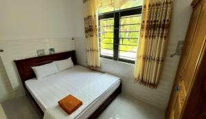a small bedroom with a bed and a window at Phu Nam House - Resort in Phú Quốc