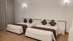 2 camas en una habitación de hotel con paredes blancas en K-BOSS Hotel, en Bắc Ninh