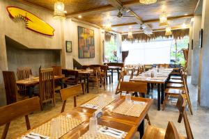 a restaurant with wooden tables and chairs and a surfboard on the wall at Haole Surf Hostel in General Luna