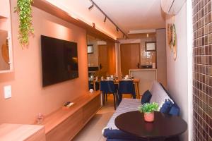 a living room with a couch and a table and a tv at Ecotambaú, Espetacular Flat Com Piscina ao Lado da Praia in João Pessoa