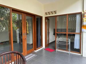 a porch with glass doors and a chair in a building at Warsa's Garden Bungalow and Spa in Ubud