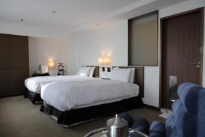 a hotel room with two beds and a couch at United Hotel in Taipei