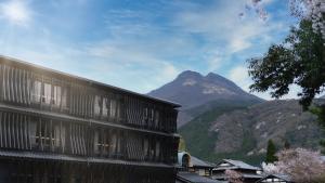 a building with a mountain in the background at Enokiya Ryokan in Yufuin