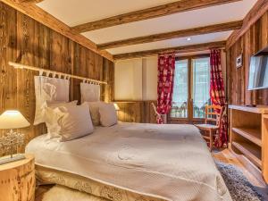 ein Schlafzimmer mit einem Bett in einem Zimmer mit Holzwänden in der Unterkunft Appartement 112m² Courchevel 1850, centre, proche pistes, 3 chambres, balnéo, hammam, WIFI - FR-1-631-165 in Courchevel