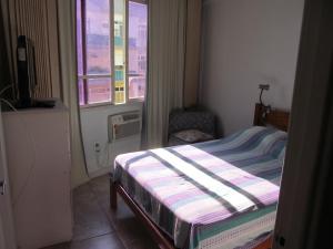um pequeno quarto com uma cama e uma janela em apartamento Edificio Master no Rio de Janeiro