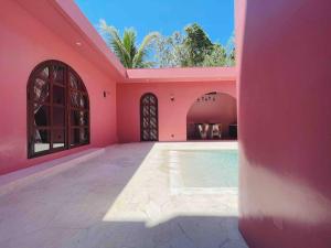 een roze huis met een zwembad erin bij VA Villa Jimbaran Bali in Jimbaran