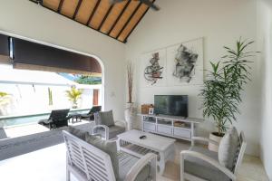 a living room with white furniture and a tv at Villa Shanti Bingin in Uluwatu