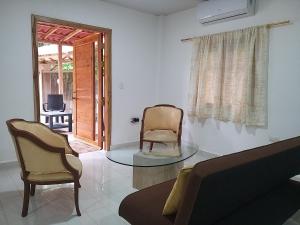 uma sala de estar com duas cadeiras e uma mesa de vidro em Nueva Tierra em Las Tunas