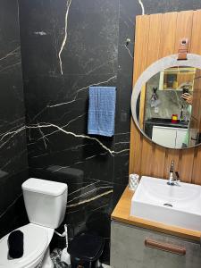 a bathroom with a toilet and a sink and a mirror at Meu Loft Barra Nova 3 in Saquarema
