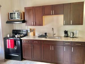 a kitchen with brown cabinets and a sink and a stove at Skyline Suites Grenada in Grand Anse