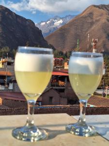 two glasses of wine sitting on a table with a view at Chaska valle Inn in Urubamba