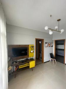 a living room with a tv and a yellow cabinet at Apartamento Moderno - Centro Luís Eduardo Magalhães - Mobiliado in Luis Eduardo Magalhaes