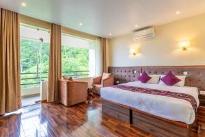 a bedroom with a bed and a large window at Sky Garden Resort in Dhulikhel