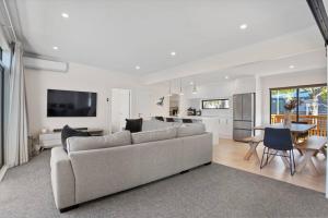 a white living room with a couch and a kitchen at Another on Leo in Waihi Beach