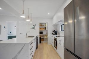 a kitchen with white counters and a stainless steel refrigerator at Another on Leo in Waihi Beach