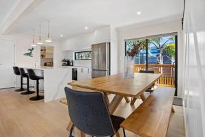a kitchen and dining room with a wooden table and chairs at Another on Leo in Waihi Beach