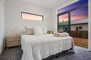 a bedroom with a bed and a large window at Another on Leo in Waihi Beach +7 photos