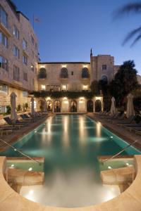 a swimming pool with chairs and a building at The American Colony Hotel - Small Luxury Hotels of the World in Jerusalem