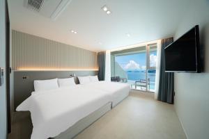 a bedroom with a large white bed and a large window at Stone Island Pool Villa in Yeosu