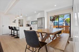 una cucina e una sala da pranzo con tavolo e sedie in legno di Leisure on Leo a Waihi Beach