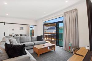 a living room with a couch and a table at Leisure on Leo in Waihi Beach