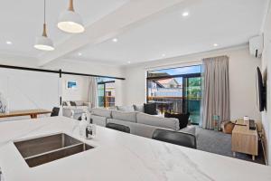 uma cozinha e sala de estar com um sofá e uma mesa em Leisure on Leo em Waihi Beach