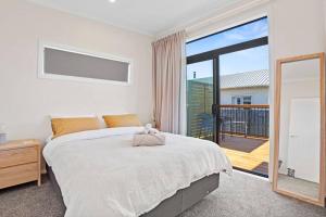 1 dormitorio con 1 cama grande y balcón en Leisure on Leo, en Waihi Beach
