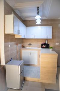 uma pequena cozinha com armários brancos e um lavatório em residence queen house em Brazavile