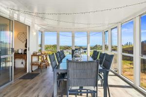 a dining room with a table and chairs and windows at Beachfront Favourite - Foxton Beach Holiday Home in Foxton Beach