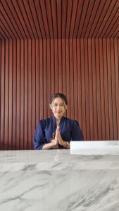 uma mulher sentada numa mesa numa sala em core inn juwita hotel em Kepanjen