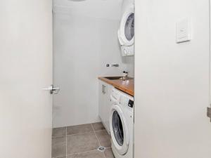 a white laundry room with a washer and dryer at 'Luxury Waterfront' Spectacular Oasis in the City in Cairns