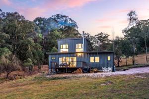 a house on a hill with trees in the background at Delightful Container House with Views in Hartley