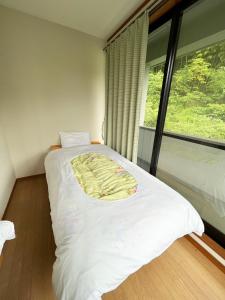 a bedroom with a white bed with a large window at シークレットベースゆふいん in Yufu