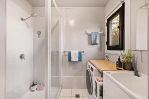 a white bathroom with a shower and a sink at Delightful Container House with Views in Hartley +29 photos