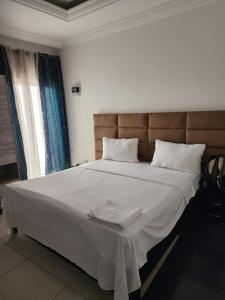a bedroom with a large bed with white sheets at appartement nid in Brazzaville