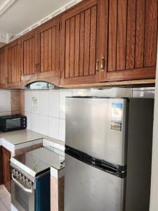 a kitchen with wooden cabinets and a stainless steel refrigerator at appartement nid in Brazzaville