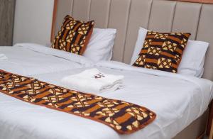 2 camas con sábanas y almohadas marrones y blancas en VIJIJI HOTEL & CONFERENCE, en Eldoret