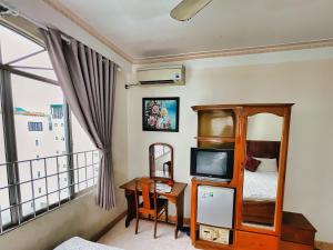 1 dormitorio con 1 cama y escritorio con TV en Quang Vinh 2 Hotel, en Nha Trang